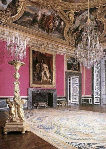 A building in Versailles with raspberry red damask walls that are elaborate and ornate i